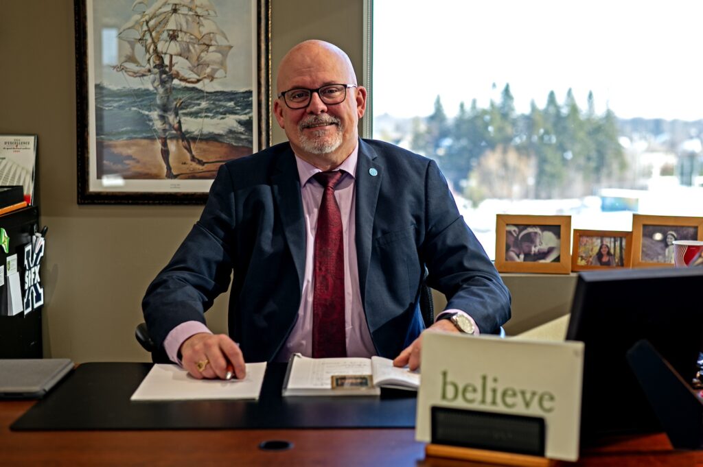 Director General George Singfield smiling at the camera while sitting at his desk. 