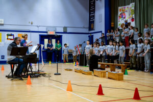 Teacher Laura McArthur and Anna Robertson (not seen here) help conduct the 80+ students performing