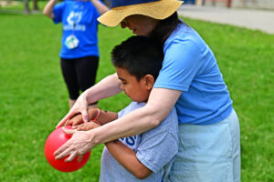 Resource teacher from PETES helps a student with how to place their fingers in a bowling ball
