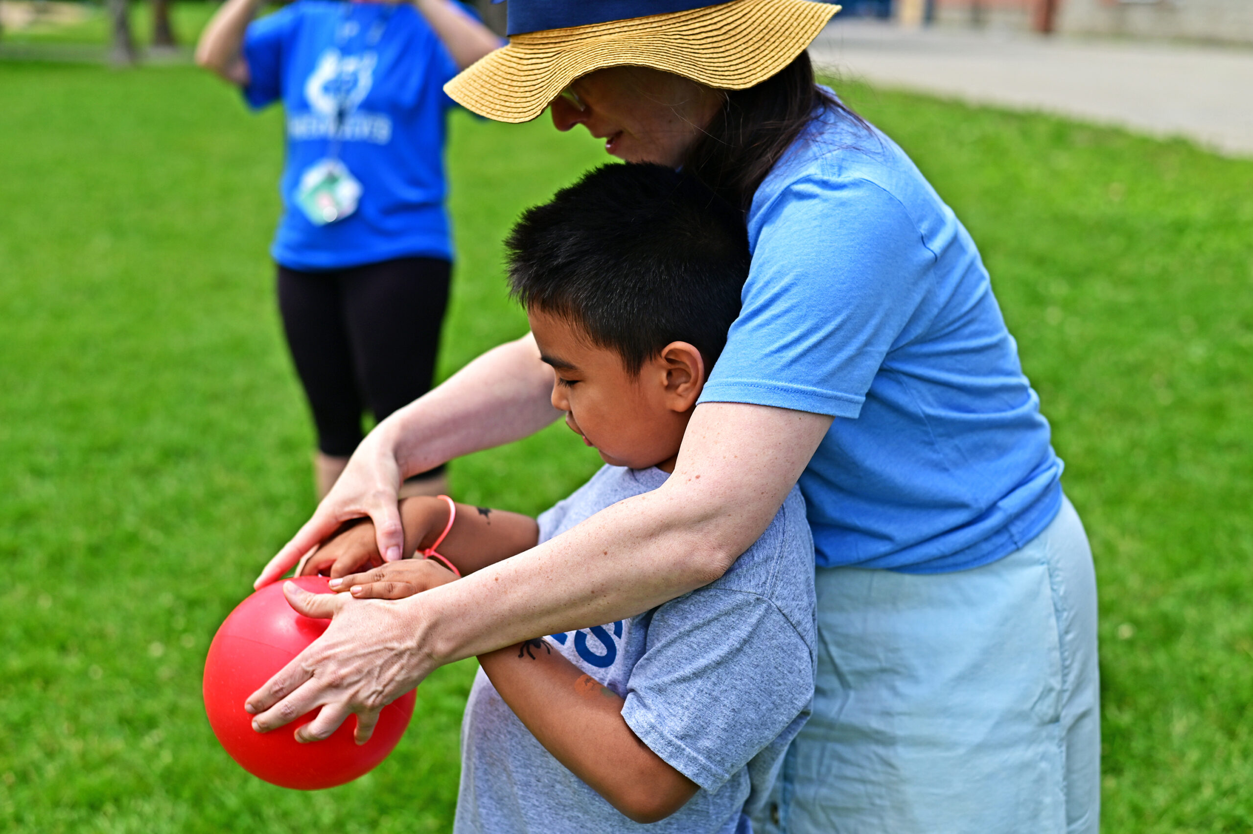 Resource teacher from PETES helps a student with how to place their fingers in a bowling ball