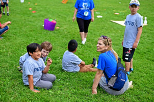 PETES students sitting on the grass patiently waiting for their turn to play