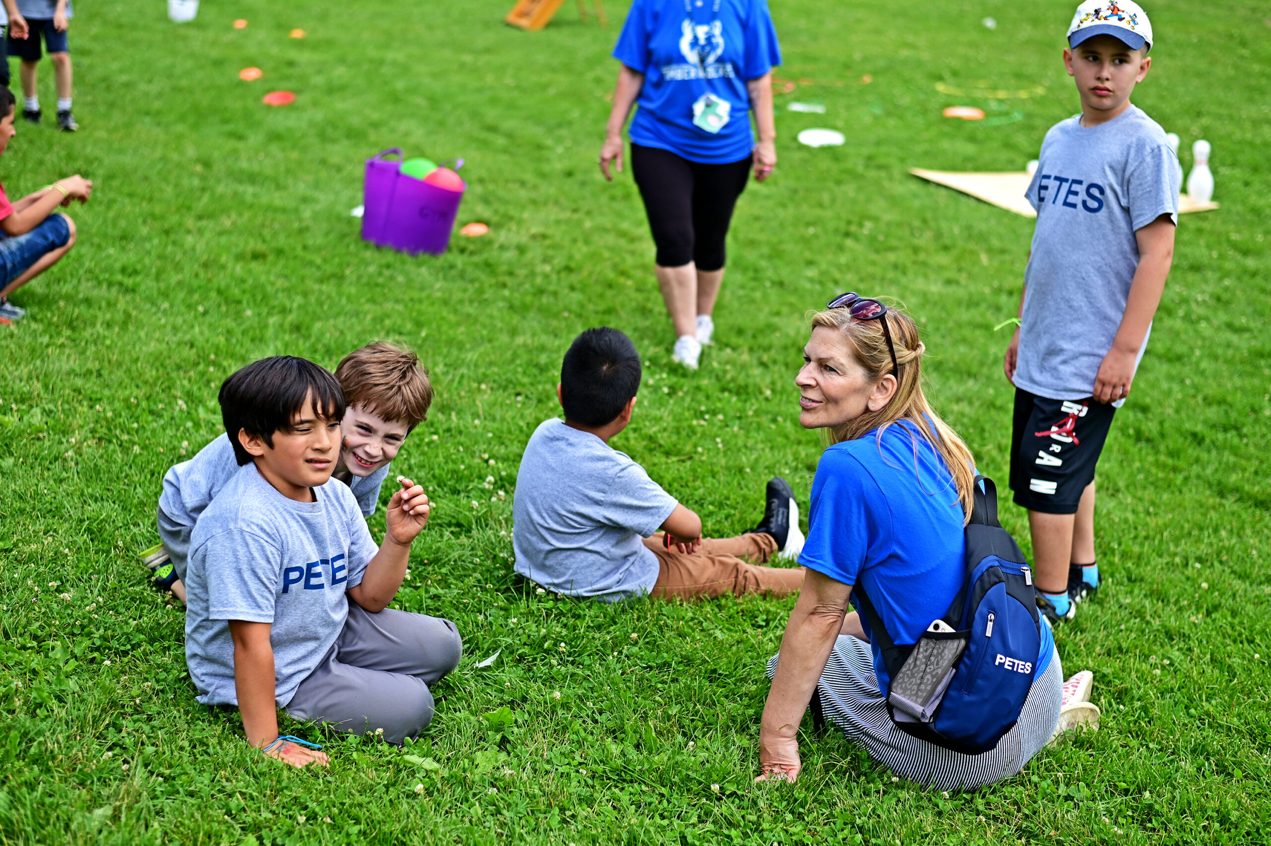 PETES students sitting on the grass patiently waiting for their turn to play